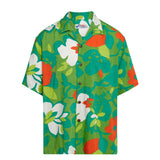 Product shot of a short-sleeve button-up shirt laid flat against a white background. The design uses a mix of bright green and dark teal for the foliage, with solid white and bold orange-red for the flowers and fruit shapes. The shirt has a camp collar, a single chest pocket, and is fastened with small, dark brown buttons.