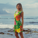 Woman in a colorful floral dress standing on a beach with ocean in the background
