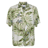 Image is a close-up shot of the Hawaiian-style shirt shown in the previous image, displayed flat against a white background. The short-sleeved collared shirt has a muted tropical print of large green, sage, and pale blue-gray leaves on a light, off-white background.
