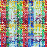 Image is a close-up of a colorful textile pattern resembling abstract vertical stripes. The design consists of repeated, small, hand-painted block shapes in red, blue, green, yellow, and white, creating a vibrant, busy texture.