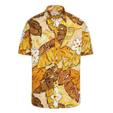 This image displays a short-sleeved, button-up Hawaiian shirt laid flat against a white background. The shirt features a vibrant pattern of tropical leaves and white hibiscus flowers in shades of golden yellow, light yellow, and dark brown.