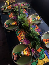 table setting with colorful table runner and napkins on green plates.