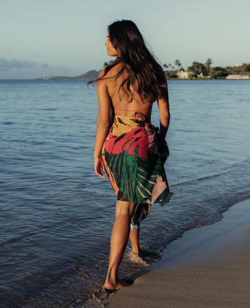 Mannequin portant un paréo fleuri coloré marchant sur la plage.