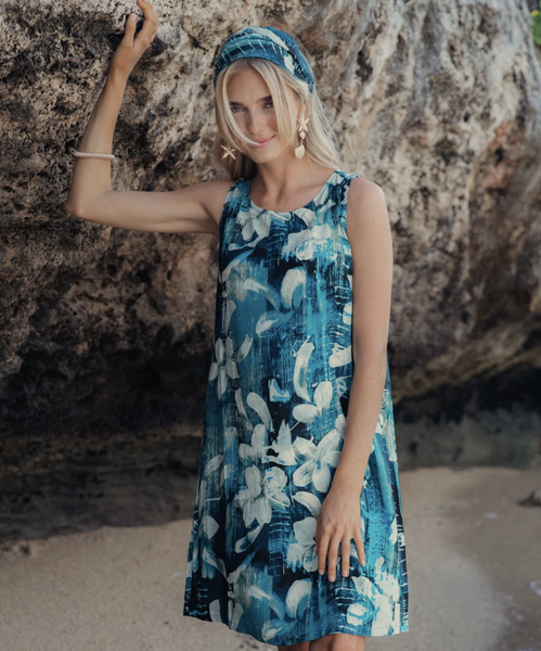 Vestido Jackie bicolor sin mangas con pañuelo a juego. Modelo de pie en la playa junto a una roca.