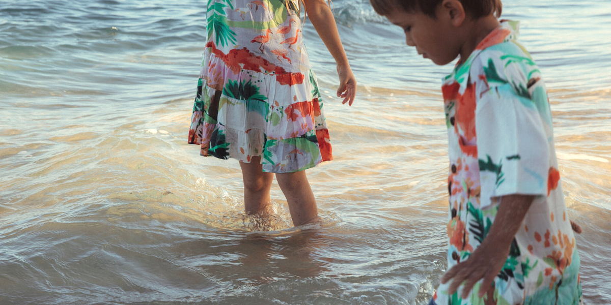 Niña y niño jugando en la playa con atuendos coloridos