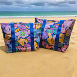 沙滩上放着两个色彩鲜艳、印有花卉图案的包。