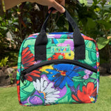 Colorful floral-patterned lunch bag held by a hand with a garden background