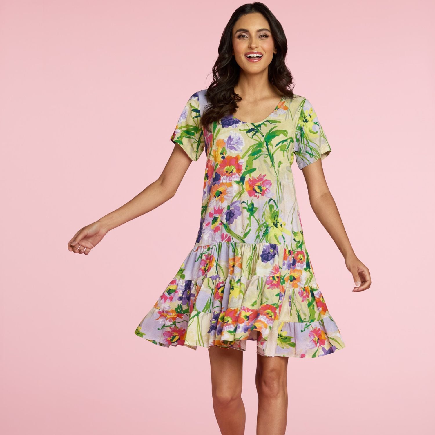 Woman wearing a colorful floral dress on a pink background