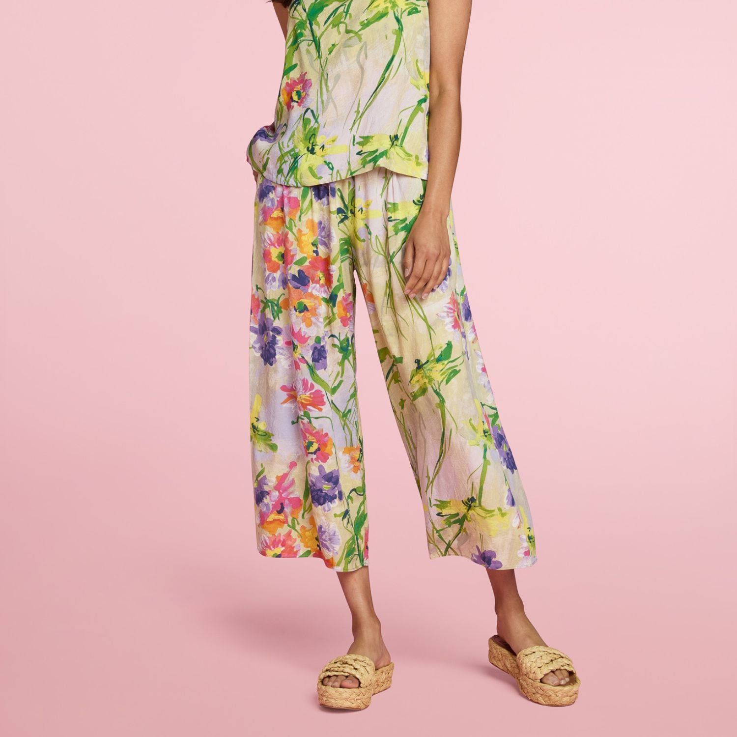Person wearing colorful floral pants on a pink background