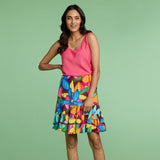 Woman wearing a pink top and colorful floral skirt on a green background