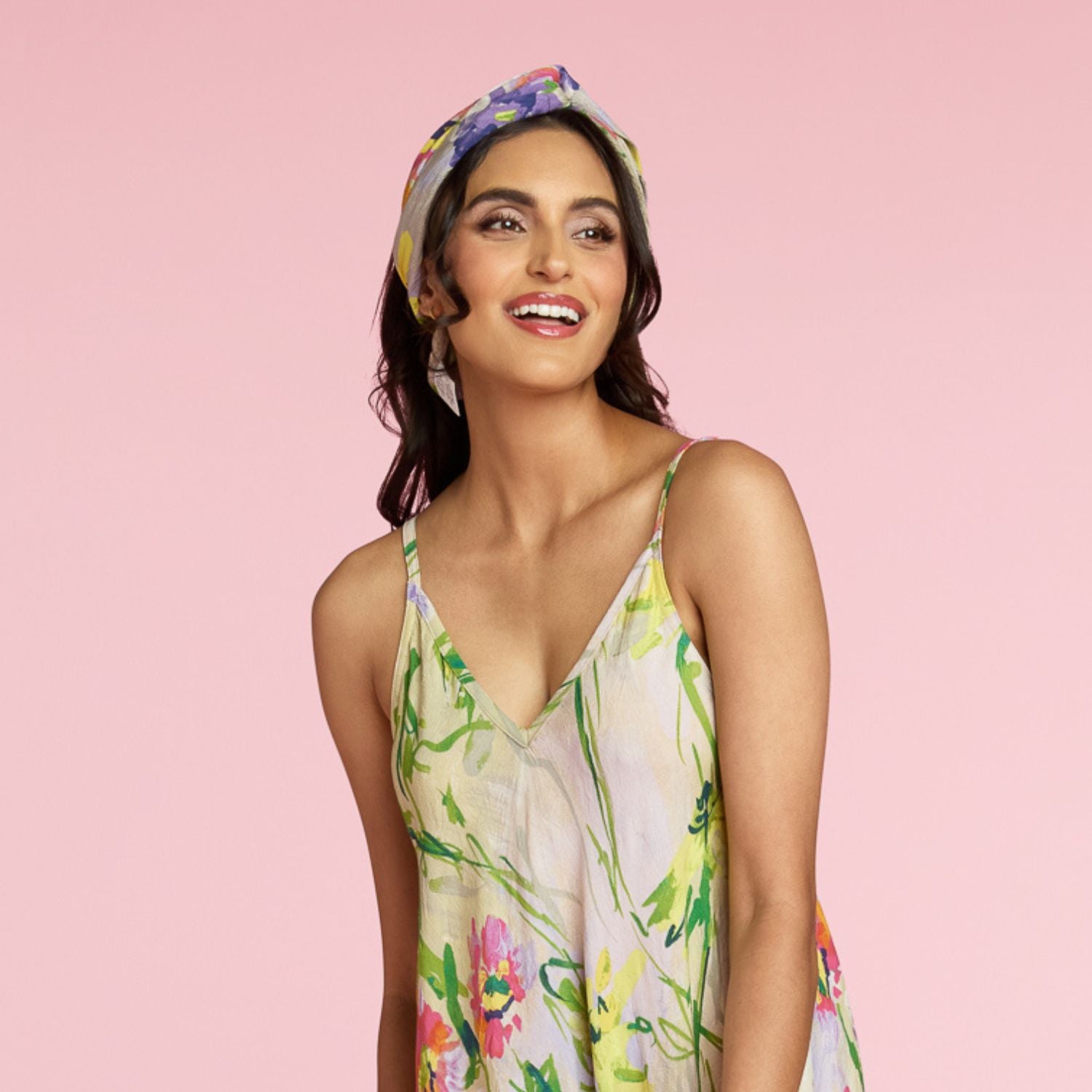 Mujer con un vestido floral y pañuelo en la cabeza sobre un fondo rosa