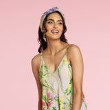 Mujer con un vestido floral y pañuelo en la cabeza sobre un fondo rosa