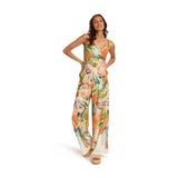 Mujer luciendo nuestra camiseta sin mangas Monstera con pantalones estampados Monstera sobre fondo blanco.