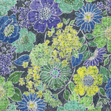 A detailed batik textile pattern featuring various hand-drawn flowers in shades of purple, turquoise, and lime green over a dark grey, crackled background.
