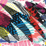 A high-contrast close-up of a fabric print featuring jagged black shapes filled with blue and yellow patterns over a pink and white background.