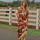 Woman in a colorful outfit standing on a road with a horse in the background