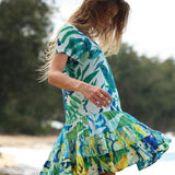 Woman wearing a colorful dress with a leaf pattern outdoors.