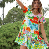 Woman wearing a colorful floral dress with a blurred green outdoor background