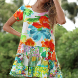 Colorful floral dress worn by a person with a blurred green background