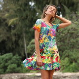 Femme vêtue d'une robe fleurie colorée, debout à l'extérieur, avec de la verdure en arrière-plan.