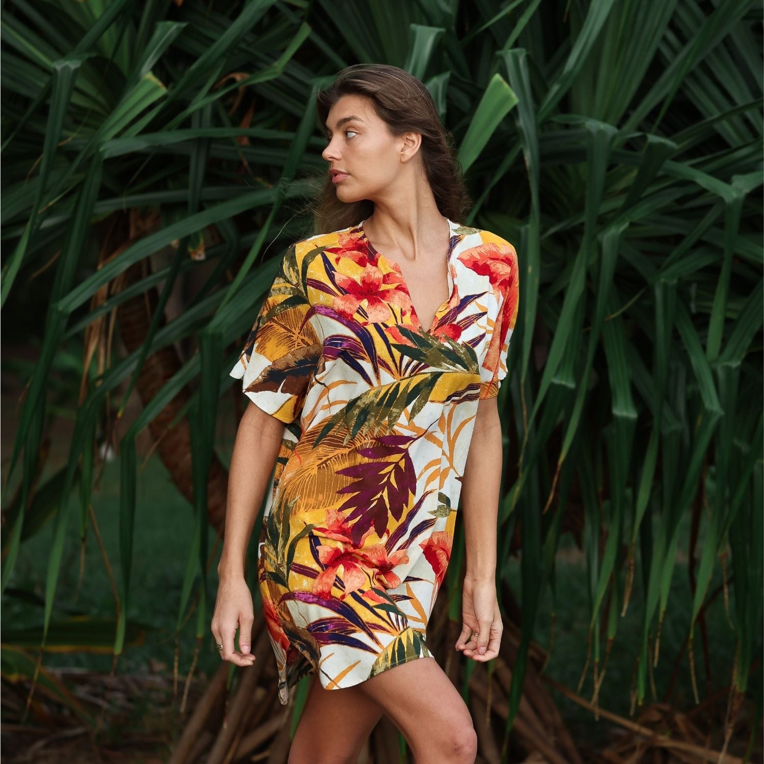 Woman wearing a colorful tropical dress standing among green plants
