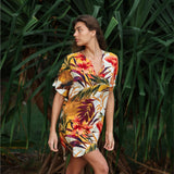 Woman wearing a colorful tropical dress standing among green plants