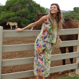 Woman in a floral outfit standing next to a horse in an outdoor setting