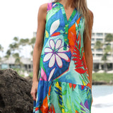 A sleeveless v-neck dress featuring a vibrant, hand-painted tropical print with large white daisies and red palm fronds.