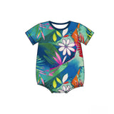 A baby onesie with short sleeves and a crew neck, featuring a bright, all-over tropical print. The design includes large white hibiscus flowers, colorful pink, green, yellow, and orange leaves, set against a watercolor background of deep blue and teal.