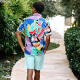 Une personne portant une chemise à motifs colorés et un short bleu clair marche à l'extérieur.