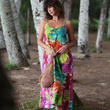 Woman in a colorful dress standing in a natural setting with trees.