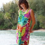 Woman wearing a colorful floral dress standing by a body of water with greenery in the background