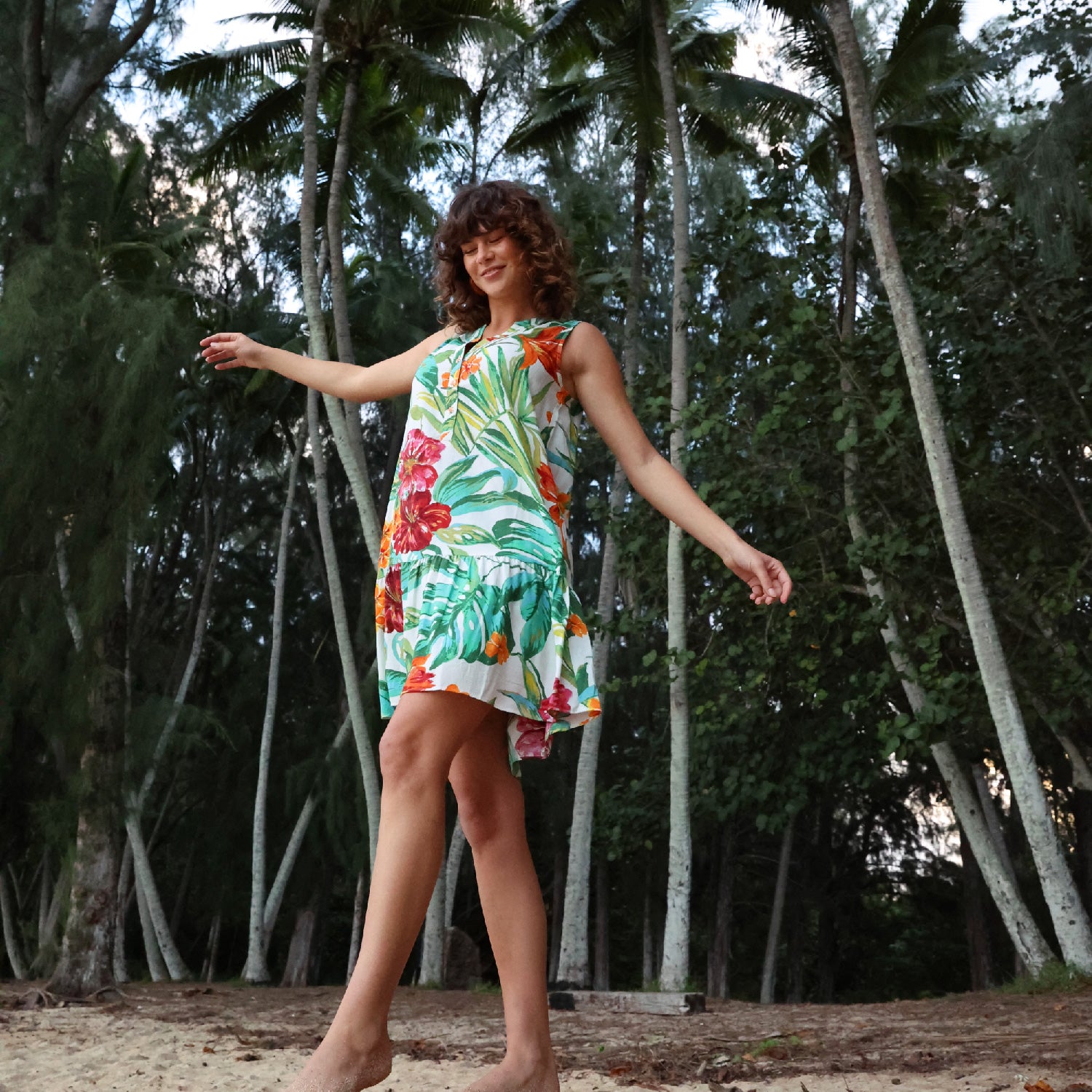 Mujer con un vestido colorido de pie en un bosque tropical