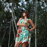 Mujer con vestido floral de pie en un entorno forestal.