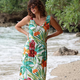 Woman wearing a colorful floral dress standing by a river with greenery in the background