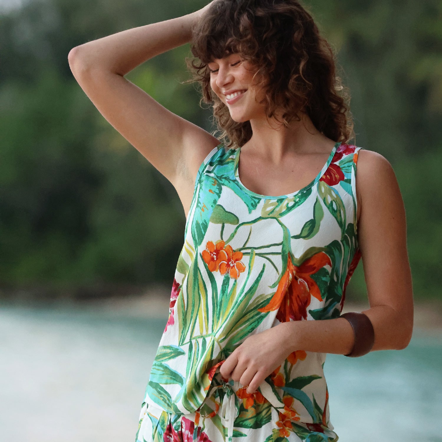 Femme en robe à fleurs au bord d'un plan d'eau avec de la verdure en arrière-plan