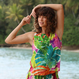 Woman wearing a colorful tropical dress by a body of water with greenery in the background