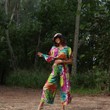 Woman in a colorful tie-dye outfit standing in a forest