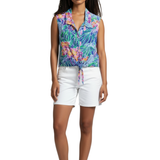 Woman wearing a colorful floral sleeveless top and white shorts on a white background