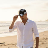 Man wearing a white shirt and black cap on a beach