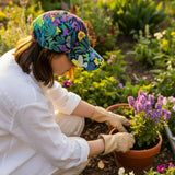 Person gardening with a colorful cap and gloves in a garden setting