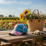 Colorful cap, sunflowers, and a straw bag on a wooden table with a garden background