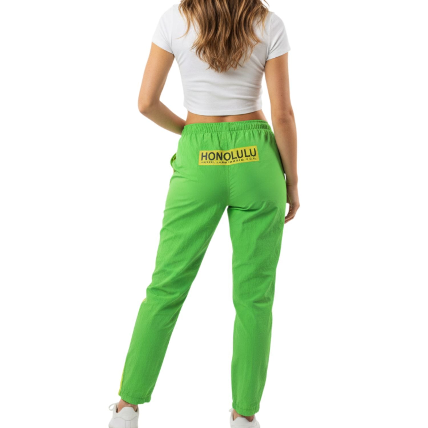 Green pants with 'Honolulu' text worn by a person on a white background