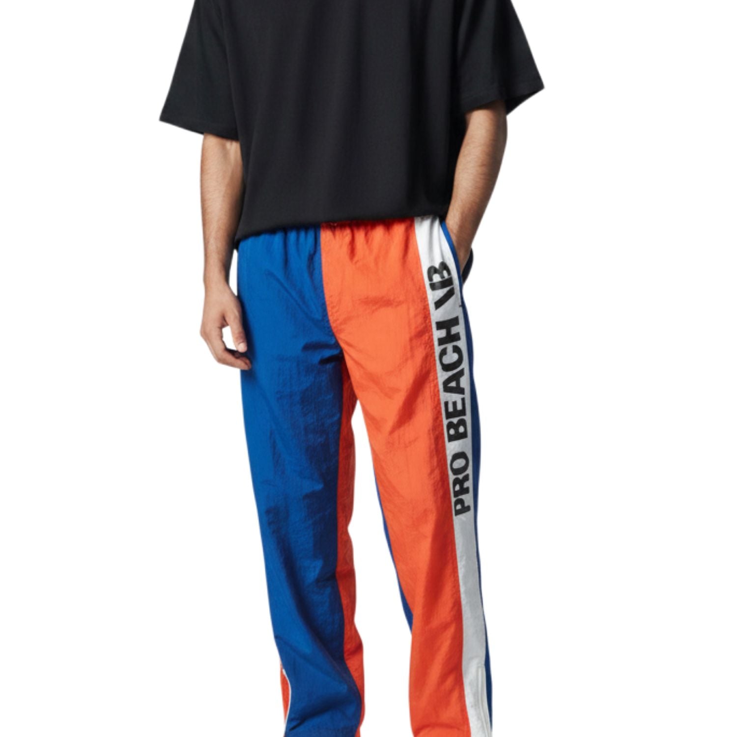 Persona que viste una camiseta negra y pantalones deportivos azules y naranjas con un logotipo de marca visible sobre un fondo blanco.