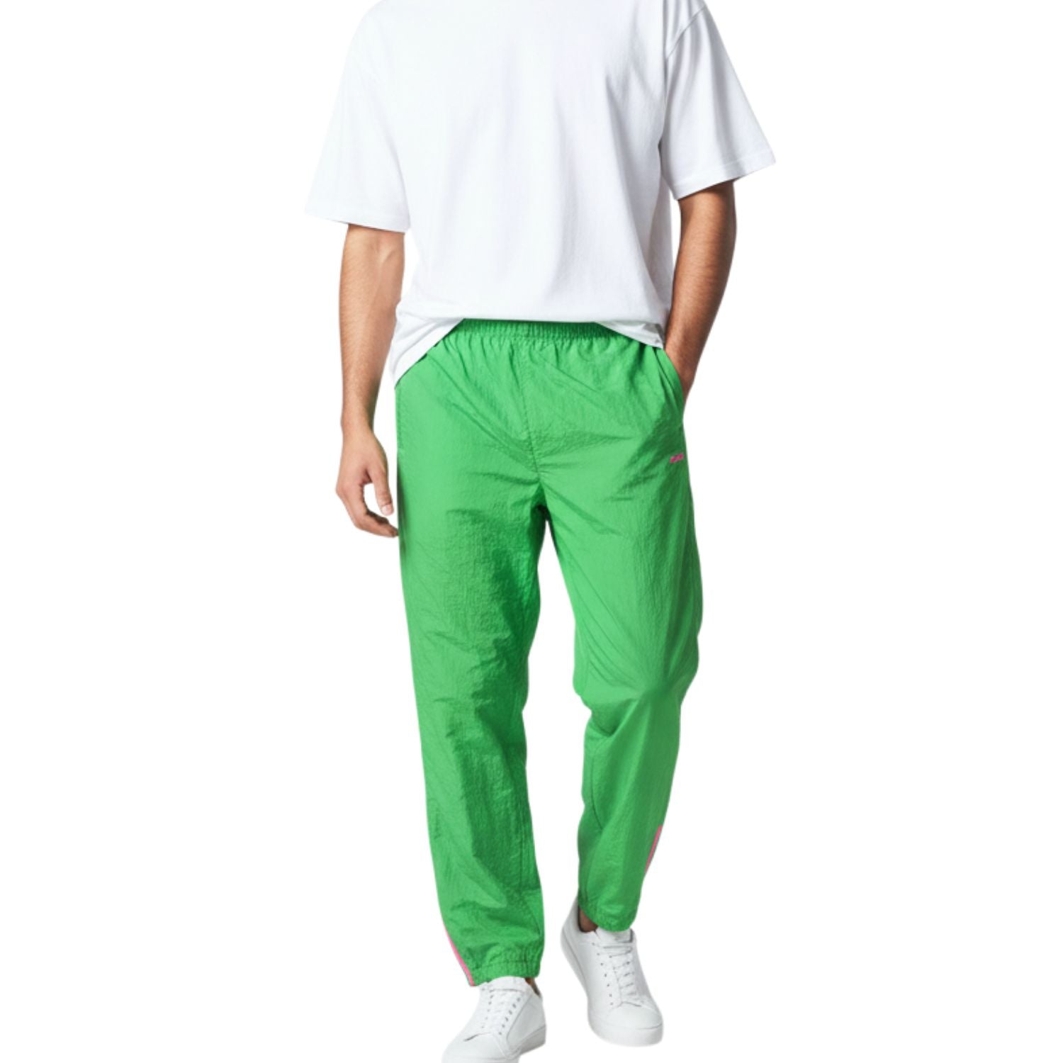 Persona que lleva pantalones de color verde brillante y una camisa blanca sobre un fondo blanco.
