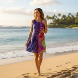 Woman in a colorful dress standing on a beach with ocean and palm trees in the background