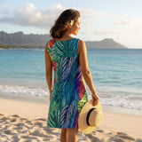 Woman in a colorful dress standing on a beach with mountains in the background