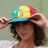 Persona con gorra colorida con texto sobre fondo verde