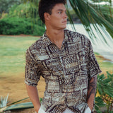 Hombre con camisa estampada en un entorno tropical con plantas.