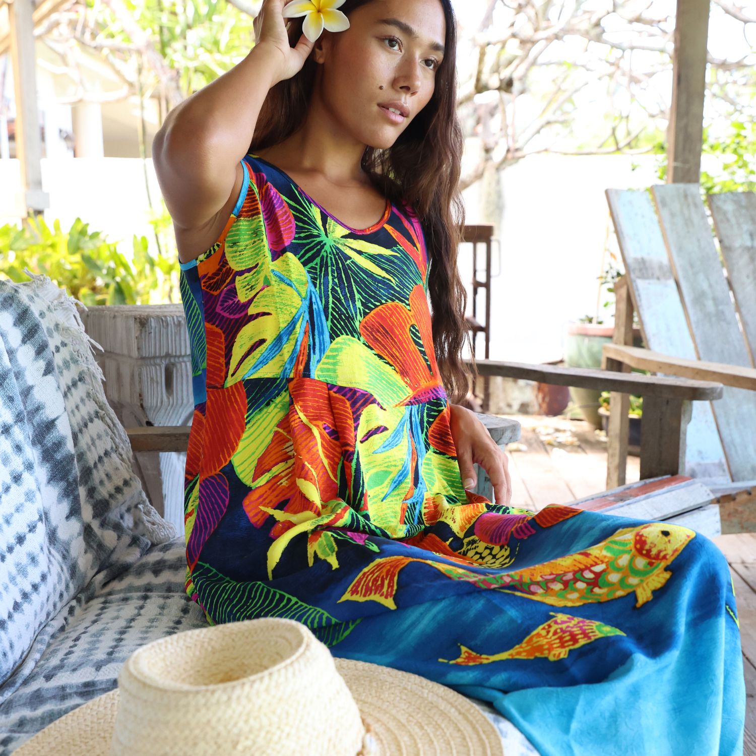 Woman wearing a colorful dress with floral patterns sitting outdoors.
